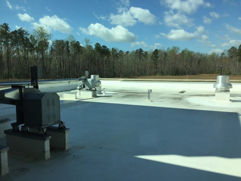 Ductwork and HVAC equipment mounted on top of a large white concrete roof