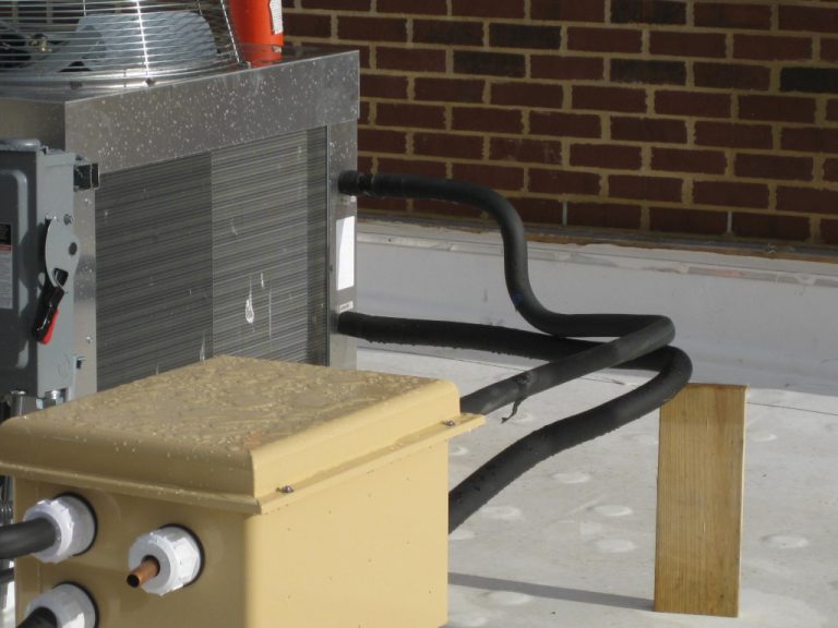 Commercial size electrical junction box sitting beside the rooftop HVAC unit that it powers