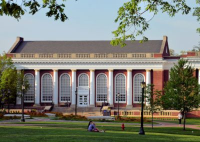 Picture across the beautifully landscaped U V A Campus lawn to the arched windows of the red brick and white columned Alderman Library