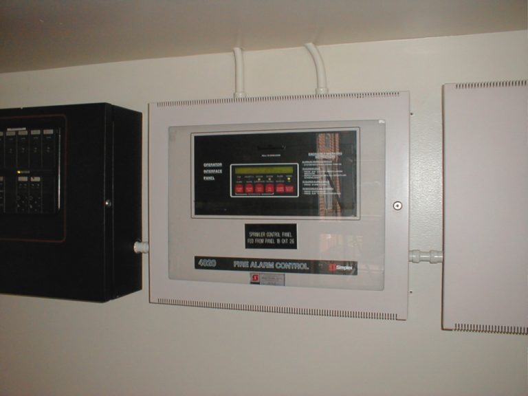 Wall mounted fire alarm control panel and a black electrical panelboard