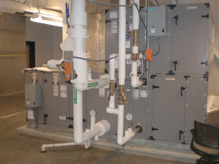 Various sizes of white pvc piping carrying the supply and return water to some of the pad mounted HVAC equipment
