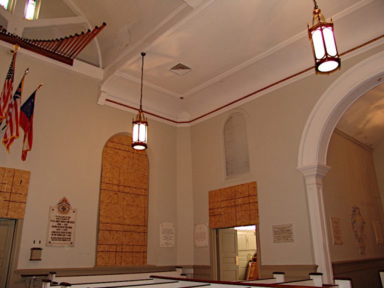 Pews and boarded arched windows at the front of the sanctuary during construction