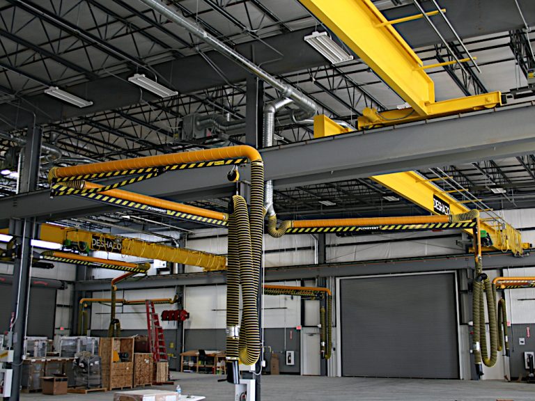 Close up view of two of the repair bays both with a vehicle exhaust extraction system suspended from a giant crossbeam that runs down the middle of the warehouse