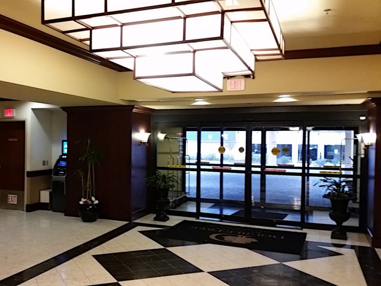 Looking out of the Doubletree Hotels' double set of automatic sliding doors to the portico from within the stylized lobby complete with black and white checkered flooring and a large multilevel smoked glass and wood art deco light fixture