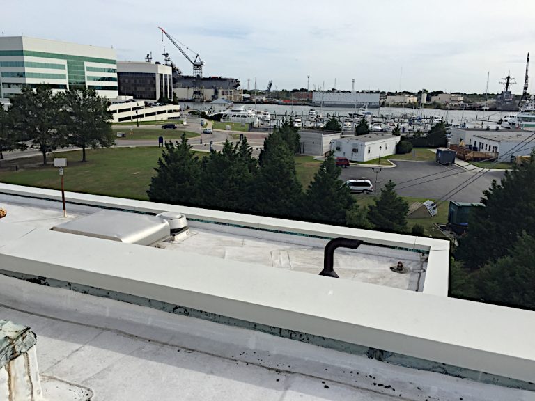 Rooftop view of piping penetrations and roof mounted fans on top of the ERC building with the parking lot and ships and boats berthed on the Elizabeth River shown in the background