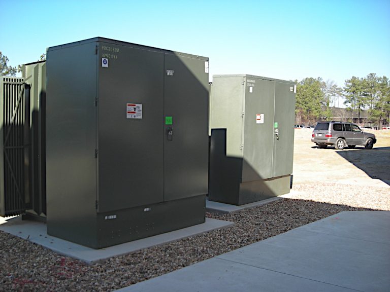Two large green transformers mounted on concrete pads located outside the Stihl building