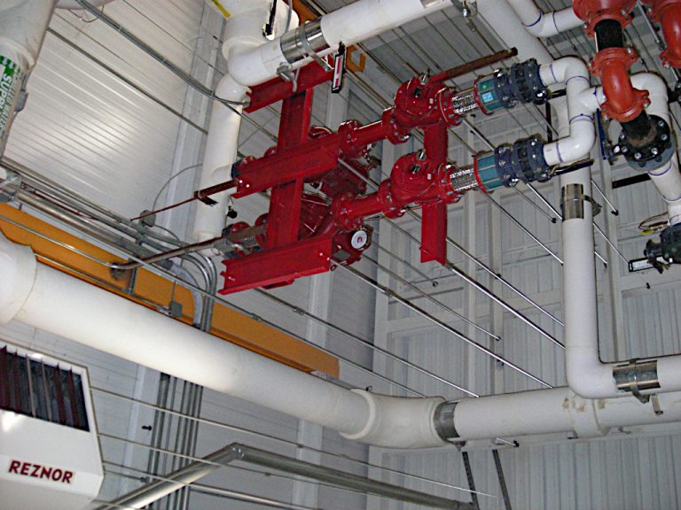 PVC and metal high pressure piping with, valves and gauges installed suspended from the ceiling in the Stihl building's mechanical room