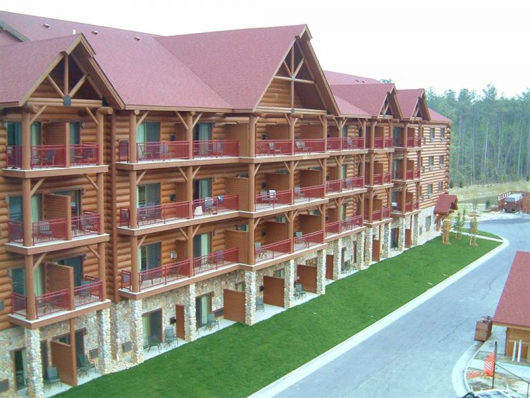 Exterior view of chairs sitting on all the private balconies of the four story cut stone and log cabin style Greatwolf Lodge