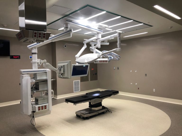 CT Scan assembly with monitors mounted from the ceiling of the new modern looking treatment room alongside the telescoping patient bed