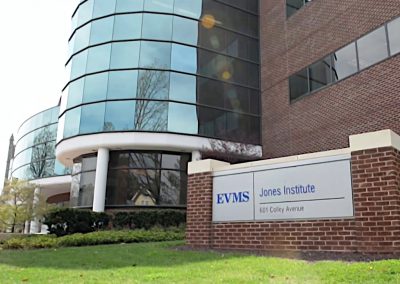 White columns under cylindrical glass alongside the brick face of the EVMS Jones Institute building in Norfolk Virginia