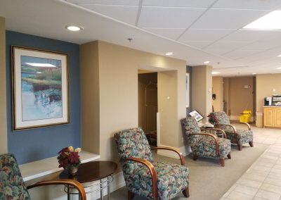 Light colored flooring and colorful tapestry upholstered chairs line the walkway of the newly renovated 4 story satellite hotel building 241