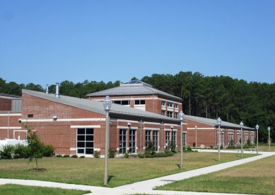 Lamp post lined sidewalks in front of landscaped beds and a modern brick building with metal and smoked glass windows