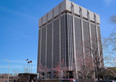 Large nine story concrete building housing the Newport New City Hall shown here with flying flags and Autumn trees in front of it