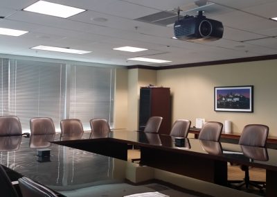 Conference room inside the Norfolk Southern Towers with a large shiny U shaped conference table and brown leather chairs underneath a ceiling mounted projector
