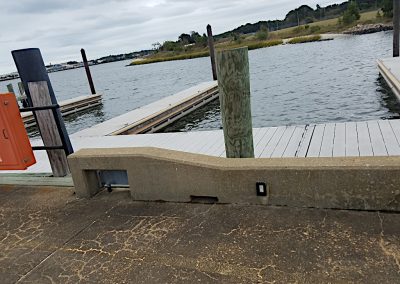 Multiple finger piers with piles at the end of them shown branching off the main floating dock at the waters edge of Little Creek Cove